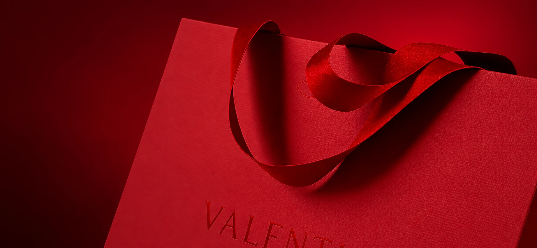 Bolsa roja de cartulina con manija de cinta, cuño en seco Valentino